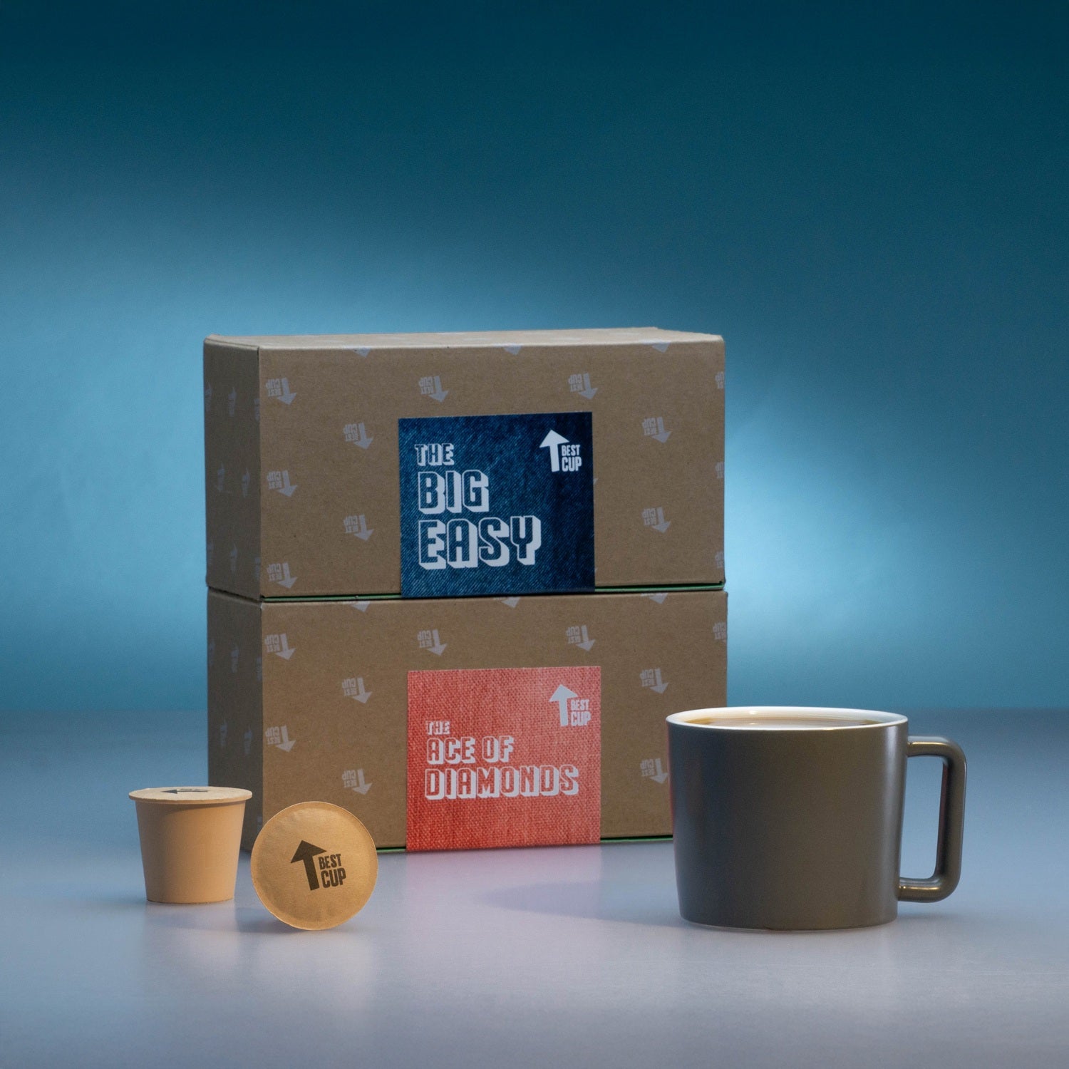 Cardboard boxes with 'The Big Easy' branding, a mug, and coffee pod on a blue gradient background.